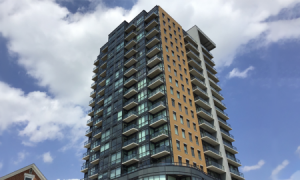 Street view of the exterior building for the One-Hundred Condominiums. A 19 story building with glass balconies.