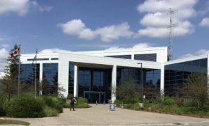 Street view of the building exterior for the Waterloo Regional Police Headquarters. Depicts glass building with walkway and shrubbery